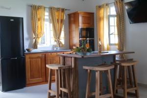 a kitchen with a black refrigerator and wooden cabinets at Logement « Indigo » in Capesterre