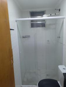 a white bathroom with a shower and a toilet at Casinha da Alê in Mongaguá