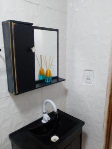 a bathroom with a black sink and a mirror at Casinha da Alê in Mongaguá +8 photos
