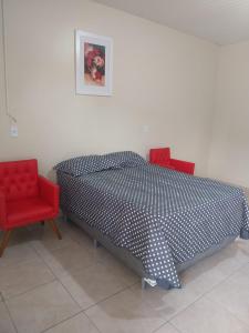 a bedroom with a bed and two red chairs at APT Raphis C in Santarém