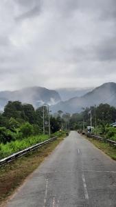 an empty road with mountains in the distance at AA Homestay in Mulu