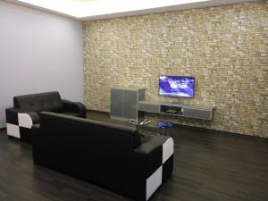 a room with two chairs and a tv on a brick wall at Vista Vacation Homestay in Melaka
