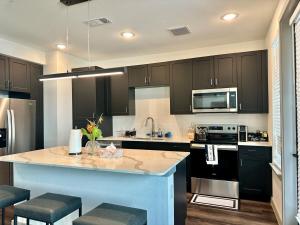 a kitchen with black cabinets and a kitchen island with stools at Cozy apartment near downtown HTX in Houston