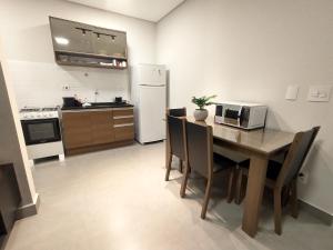 uma cozinha com uma mesa com cadeiras e um frigorífico branco em Residencial Verônica 06 - Apartamento de 1 quarto próximo ao centro em Marília