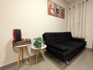 uma sala de estar com um sofá preto e uma mesa em Residencial Verônica 06 - Apartamento de 1 quarto próximo ao centro em Marília