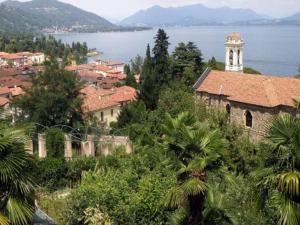 a town with a clock tower on a hill next to the water at Belle Epoque Belvilla by OYO in Meina