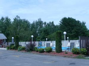 une clôture blanche avec piscine dans un parking dans l'établissement Motel Marie-Dan, à Sainte-Eulalie