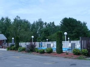 uma cerca branca com uma piscina num parque de estacionamento em Motel Marie-Dan em Sainte-Eulalie