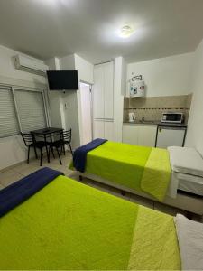 two beds in a room with a table and a kitchen at Terminal 1 in Villa María