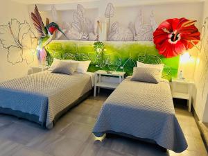 アンティグア・グアテマラにあるHotel y Arte Antigua by Amazing Guatemala Travelの花が壁に飾られた部屋のベッド2台