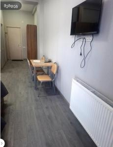 a room with a table with chairs and a television on the wall at ახალი გუდაური საბაგიროსთან in Gudauri