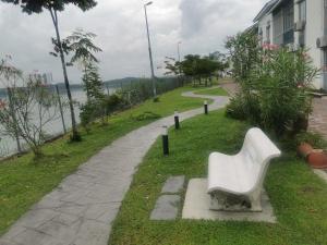 a white bench sitting on the grass next to a sidewalk at Lake Residence No165 @aesthetic lake view & best photograph in Puchong