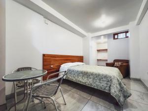 a bedroom with a bed and a table and chair at Excelente ubicación! Bellas y cómodas habitaciones en el centro de Oxapampa in Oxapampa