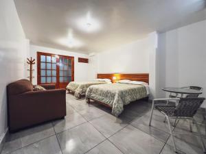 a bedroom with two beds and a table and a couch at Excelente ubicación! Bellas y cómodas habitaciones en el centro de Oxapampa in Oxapampa