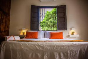 a bed with two orange pillows and a window at Hotel Capilla del sol in Garzón +57 photos