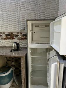 Un refrigerador vacío con la puerta abierta en una cocina. en Cozy airconditioned two bedroom apartments شقق فندقية مكيفة للإيجار, en Ras El Bar