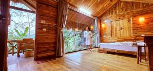 een vrouw in een slaapkamer met een bed en een raam bij Ecolodge Kê Nênh Điện Biên in Ban Hin Lom +70 foto's