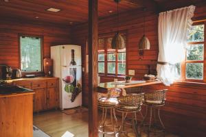 a kitchen with a refrigerator and a counter with stools at Chalé Recanto do Vale pomerode in Pomerode