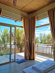 une chambre avec un lit et un balcon avec fenêtres dans l'établissement Hòn Đỏ Homestay Ninh Thuan Venuestay, à Mỹ Thanh