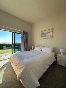 Un dormitorio con una cama grande y una ventana grande. en Coastal Paradise, en Raglan