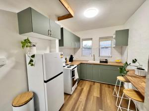 a kitchen with green cabinets and a white refrigerator at Stylishly Renovated Abode in South Hedland