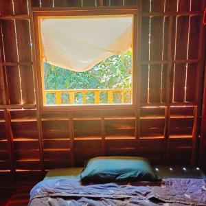 a window in a room with a bed in front of it at Green Garden Food Forest Buriram in Ban Thung Nak