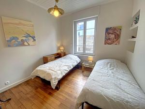 una camera da letto con due letti e una finestra di Maison familiale rénovée à 150m des criques, 4 chambres, jardin privé, cheminée, parking, WiFi - FR-1-349-222 a Port-Louis