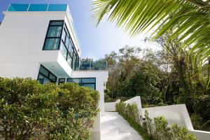 una casa blanca con árboles y arbustos en Namara The Residences B, en Kamala Beach