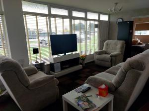 a living room with two chairs and a flat screen tv at Grand Chalet 64 Disabled Friendly in Skegness