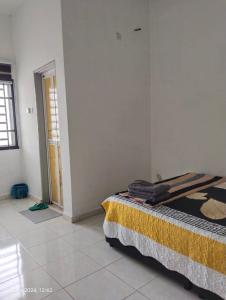 a bedroom with a bed with a yellow blanket on it at Izani Homestay in Bandar  Pusat Jengka