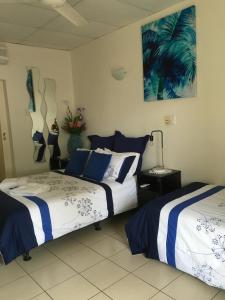 a bedroom with two beds with blue and white sheets at Black Marlin Motel in Innisfail