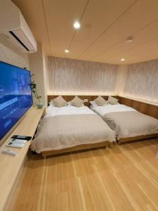 a bedroom with two beds and a flat screen tv at M house asakusa kaminarimon tokyo in Tokyo