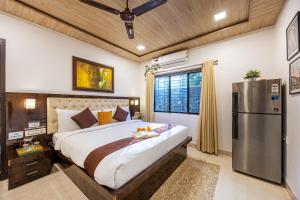 a bedroom with a large bed and a refrigerator at SaffronStays Olive Greens, Karjat in Karjat