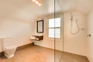 a bathroom with a toilet and a glass shower stall at Brampton Cottage in Hobart +11 photos