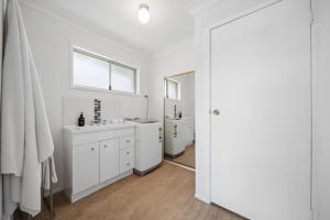 a white bathroom with two sinks and a window at Tides & Tails Abode - Coolum Beach Pet Friendly Home in Coolum Beach