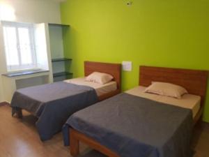 two beds in a room with green walls at Coastal Grand JMA Resorts, sirumalai in Ambātturai