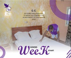a man making a bed in a hotel room at Lively Hotel Makepe in Douala +1 photo
