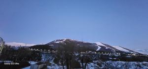 a mountain covered in snow with a town in the background at Квартира in Jermuk