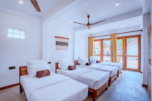 The Green Rooms Surf & Yoga Camp - ON THE BEACH - Prime location Renovated 2024 في يليغاما: صف من الأسرة في غرفة مع نوافذ