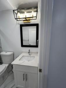 a white bathroom with a sink and a mirror at Cozy 2 Bedrooms Modern Basement Suite with Private entrance, Kitchen and parking in Mississauga