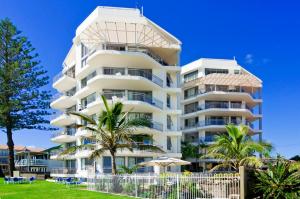 un grand bâtiment blanc avec des palmiers devant lui dans l'établissement Oceanside Resort - Absolute Beachfront Apartments, à Gold Coast