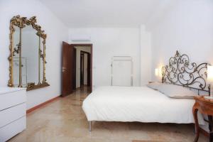 ein weißes Schlafzimmer mit einem Bett und zwei Spiegeln in der Unterkunft Castedd'House in Cagliari