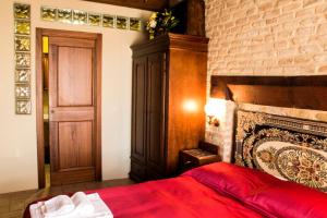 1 dormitorio con cama roja y pared de ladrillo en Al Castello di Montalfoglio en San Lorenzo in Campo