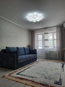 a living room with a blue couch and a window at 2-х комнатная Квартира in Uralsk