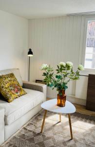 a living room with a couch and a table with a vase of flowers at Charmante Wohnung im alten Dorfkern in Winterthur