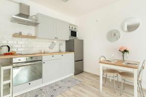 a kitchen with white cabinets and a table with chairs at Spacious Apartment with Balcony in Gdańsk by Rent like home in Gdańsk