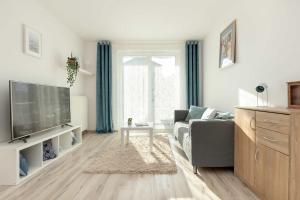 a living room with a couch and a tv at Spacious Apartment with Balcony in Gdańsk by Rent like home in Gdańsk