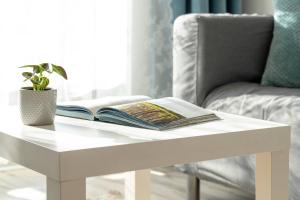 a white coffee table with a book and a plant on it at Spacious Apartment with Balcony in Gdańsk by Rent like home in Gdańsk