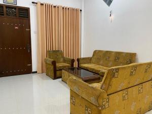 a living room with a couch and chairs and a door at Labuduwa Rest in Galle