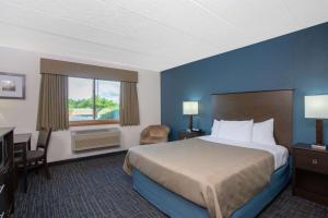 a hotel room with a bed and a desk and a window at AmericInn by Wyndham Hayward in Hayward +22 photos